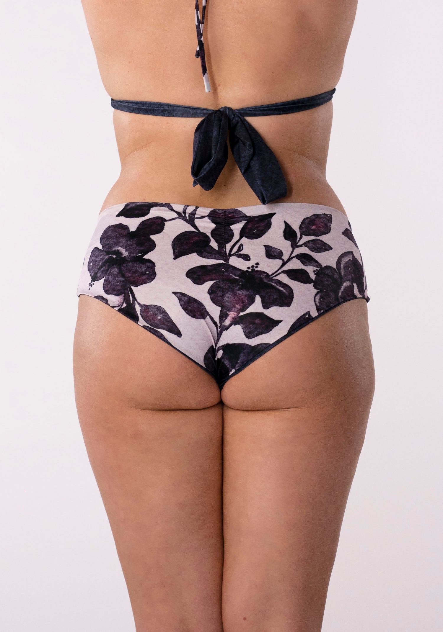 Low rise bikini bottoms with a boyish leg line to look cute and flirty! These reversible swim bottoms feature a navy blue watercolour solid wash on one side and a feminine pale pink with navy blue floral hibiscus watercolour print on the other side. Ruched detailing on the center of the bum help to accentuate your sexy curves!