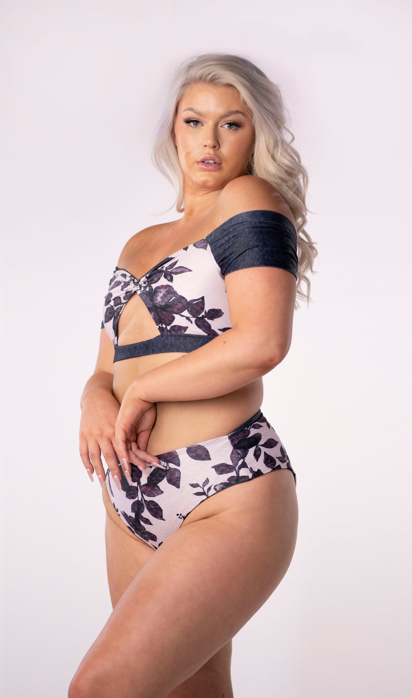 A reversible off the shoulder bikini top, solid navy blue wash on one side and on the other, a girlie pink floral pattern featuring blue hibiscus watercolour print. The front features a traingular cut away under the bust and a gathered center detail. The sleeves and broad elastic chest band neatly frame the design in solid navy blue.